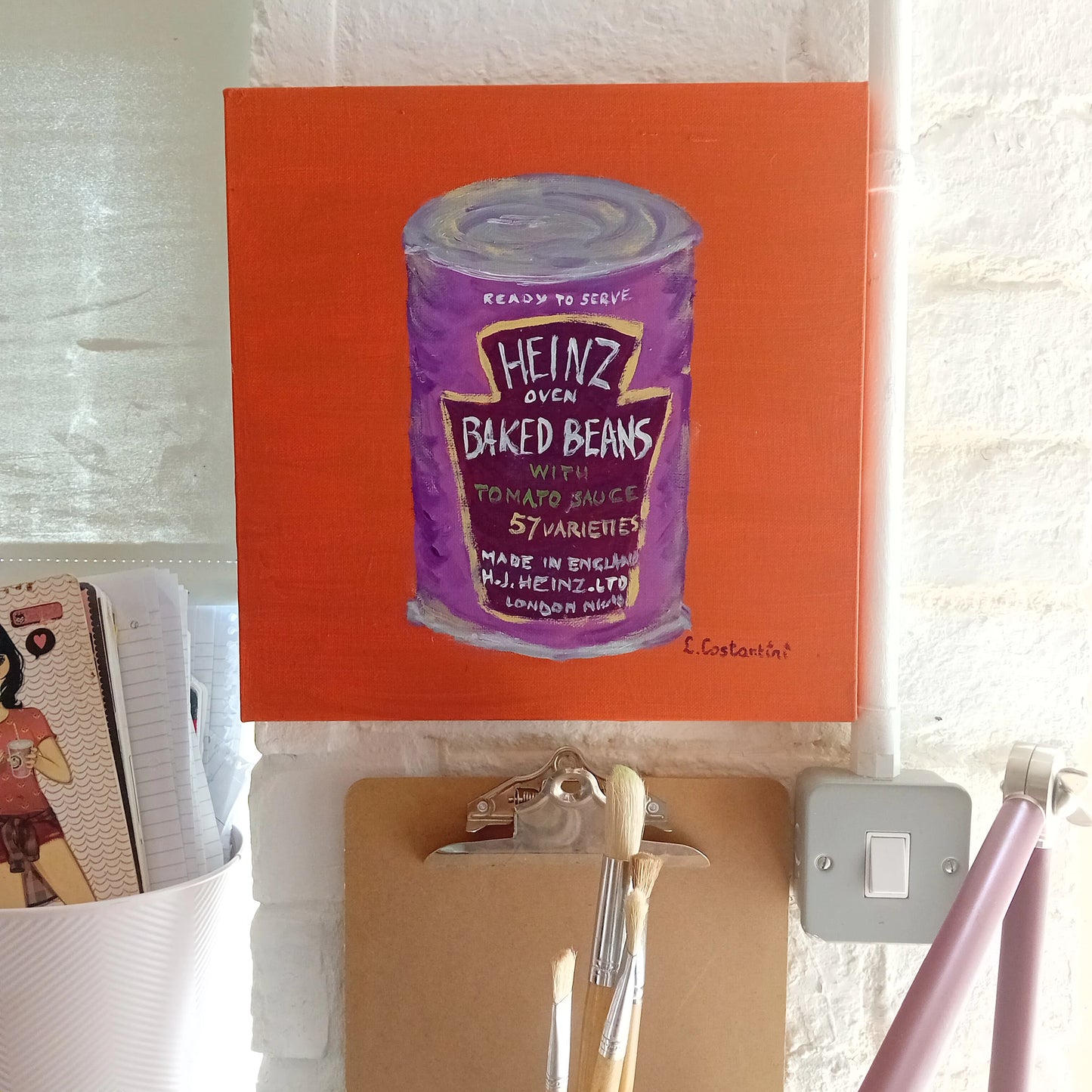 Painting of a purple Heinz baked beans can on an orange background on a white brickwall